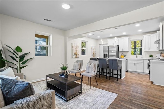 living area featuring baseboards, visible vents, wood finished floors, and recessed lighting