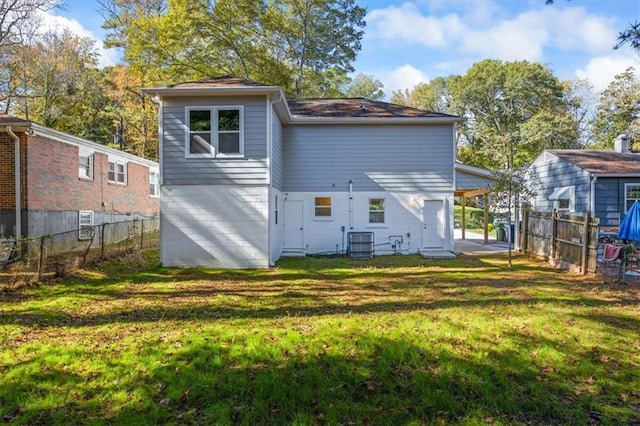 back of property with central air condition unit, fence, and a lawn