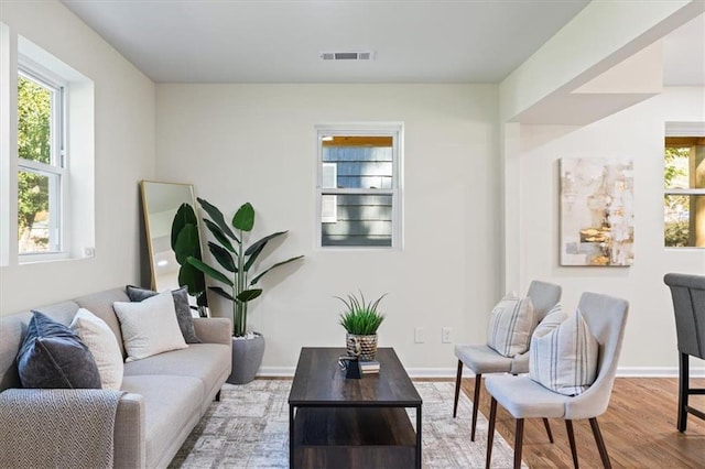 living room featuring baseboards, visible vents, and wood finished floors