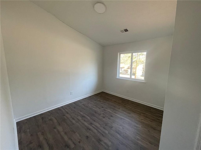 unfurnished room featuring baseboards, lofted ceiling, dark wood-style flooring, and visible vents