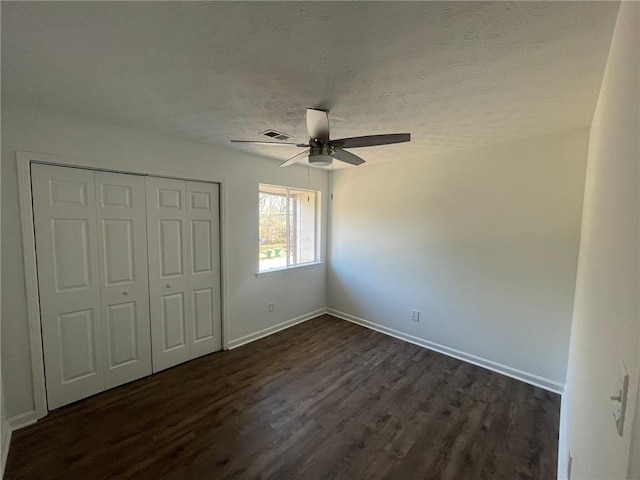 unfurnished bedroom featuring ceiling fan, visible vents, dark wood finished floors, baseboards, and a closet