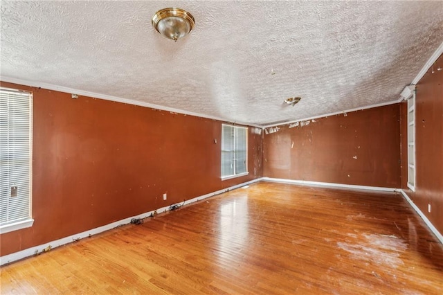 empty room with hardwood / wood-style flooring, ornamental molding, and a textured ceiling