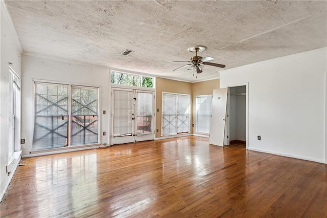 empty room featuring ceiling fan, ornamental molding, hardwood / wood-style floors, and a textured ceiling