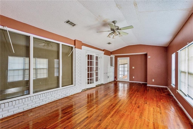 interior space featuring ceiling fan, wood-type flooring, vaulted ceiling, and a textured ceiling