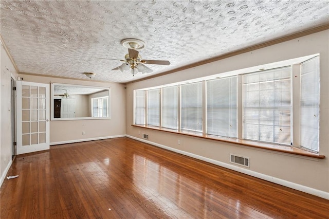 unfurnished living room with ceiling fan, ornamental molding, wood-type flooring, and a textured ceiling