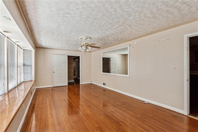 empty room featuring hardwood / wood-style flooring, ceiling fan, crown molding, and a textured ceiling