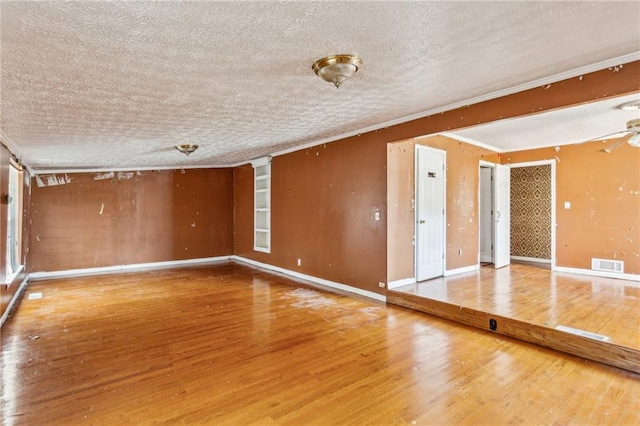 spare room featuring crown molding, hardwood / wood-style flooring, and a textured ceiling