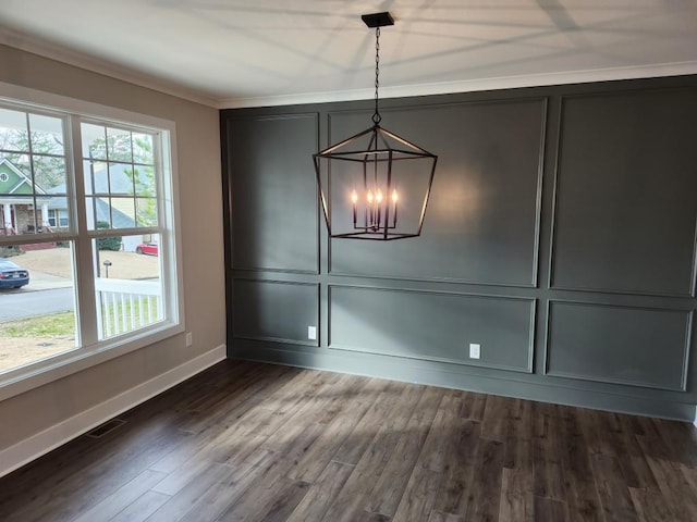 unfurnished dining area featuring crown molding, a healthy amount of sunlight, dark hardwood / wood-style flooring, and an inviting chandelier