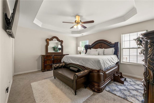 bedroom featuring multiple windows, light colored carpet, and a tray ceiling