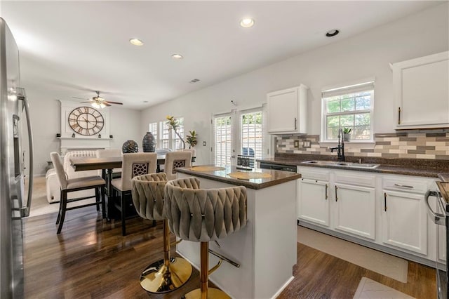 kitchen with white cabinetry, a center island, sink, and stainless steel fridge