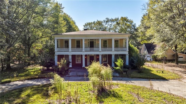 greek revival inspired property featuring a balcony and a front lawn