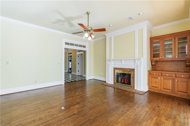 unfurnished living room featuring ceiling fan, a fireplace, dark wood-type flooring, and ornamental molding