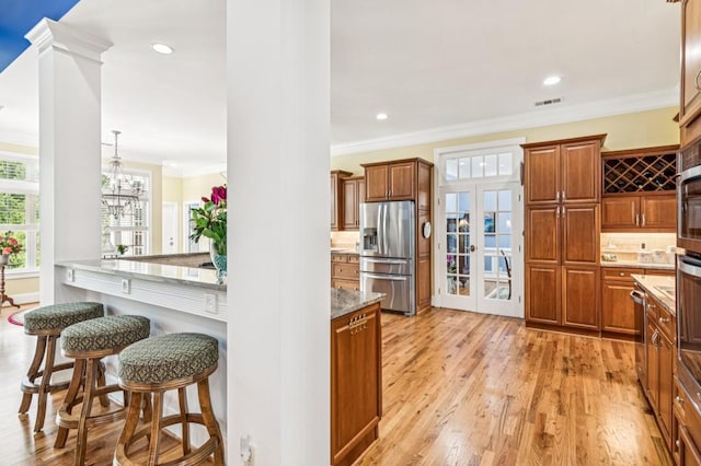317 Red Gate Overlook, Canton, GA 30115 - kitchen featuring appliances with stainless steel finishes, a breakfast bar, ornamental molding, french doors, and light wood-style floors