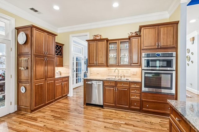 317 Red Gate Overlook, Canton, GA 30115 - kitchen with stainless steel appliances, light stone counters, brown cabinets, light wood-type flooring, and crown molding