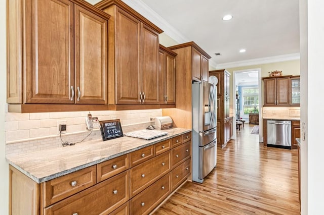 317 Red Gate Overlook, Canton, GA 30115 - kitchen with stainless steel appliances, light wood-style flooring, brown cabinets, crown molding, and light stone countertops