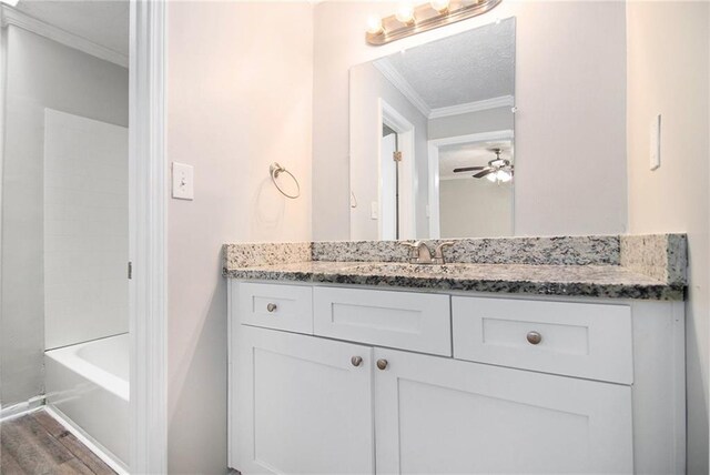 bathroom with ornamental molding, wood-type flooring, ceiling fan, and vanity