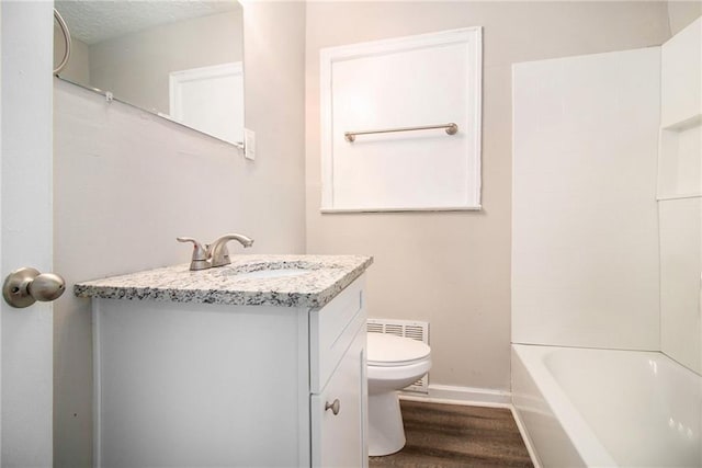 full bathroom with vanity, a textured ceiling, hardwood / wood-style floors, shower / washtub combination, and toilet