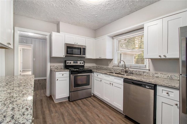 2435 Wood Valley Dr, Atlanta, GA 30344 - kitchen with appliances with stainless steel finishes, a sink, white cabinetry, dark wood finished floors, and light stone countertops