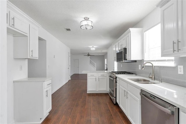 kitchen featuring sink, dark hardwood / wood-style flooring, kitchen peninsula, stainless steel appliances, and white cabinets