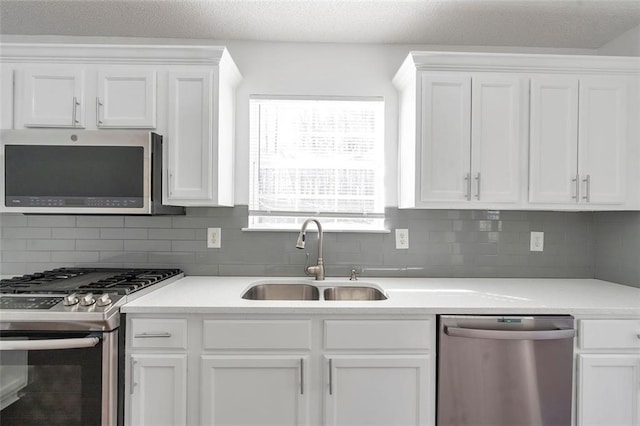 kitchen with white cabinetry, stainless steel appliances, sink, and tasteful backsplash