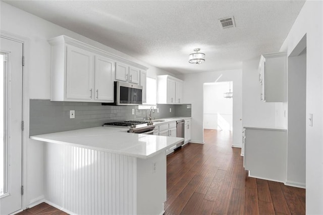 kitchen featuring sink, appliances with stainless steel finishes, kitchen peninsula, decorative backsplash, and white cabinets