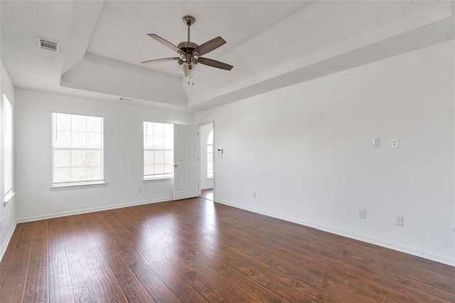 unfurnished room featuring ceiling fan, dark hardwood / wood-style floors, and a raised ceiling