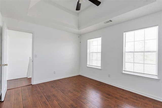 spare room featuring dark hardwood / wood-style floors, ceiling fan, and a tray ceiling