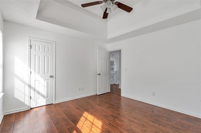 spare room featuring ceiling fan, dark hardwood / wood-style flooring, and a tray ceiling