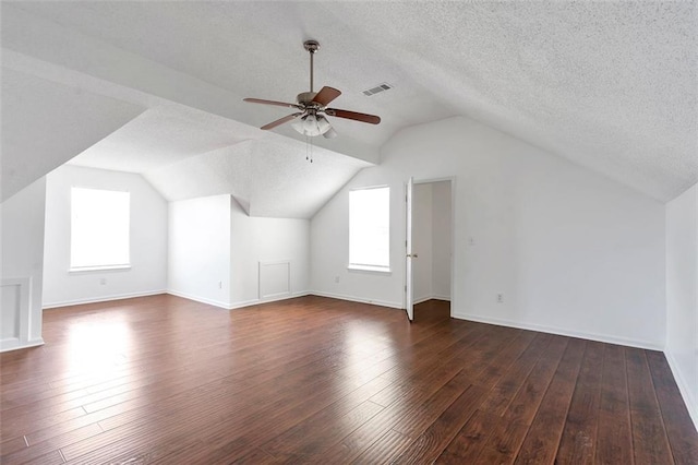 bonus room featuring ceiling fan, dark wood-type flooring, a textured ceiling, and plenty of natural light