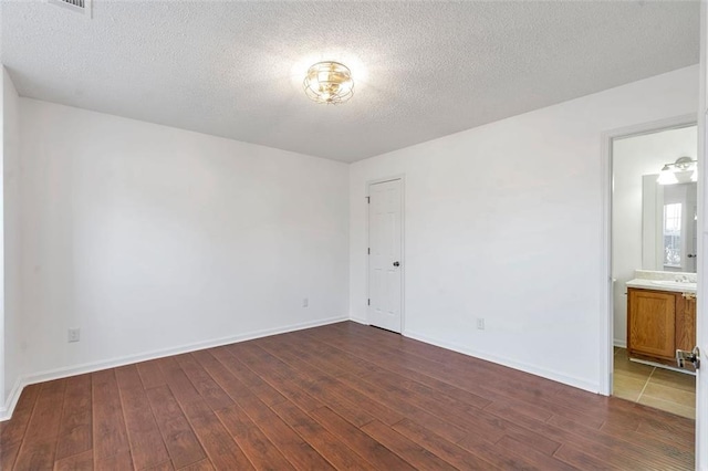 unfurnished room featuring dark wood-type flooring, sink, and a textured ceiling