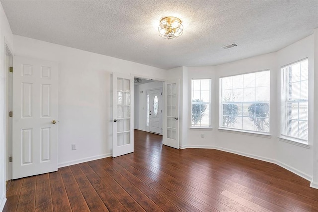 unfurnished room with dark wood-type flooring, french doors, and a textured ceiling