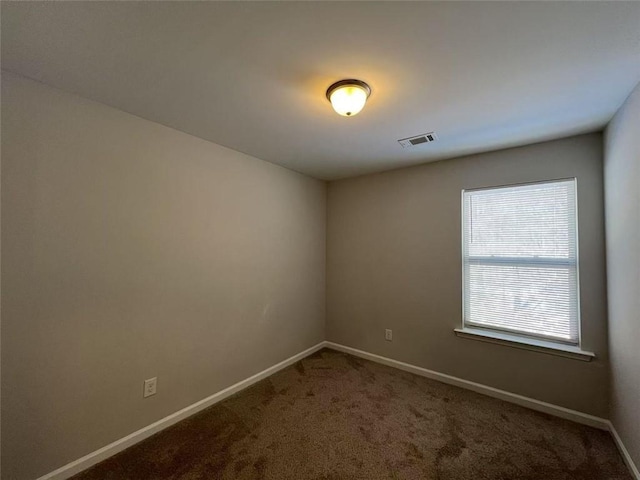 carpeted spare room featuring visible vents and baseboards