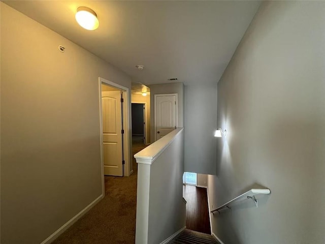 hallway featuring visible vents, carpet floors, an upstairs landing, and baseboards