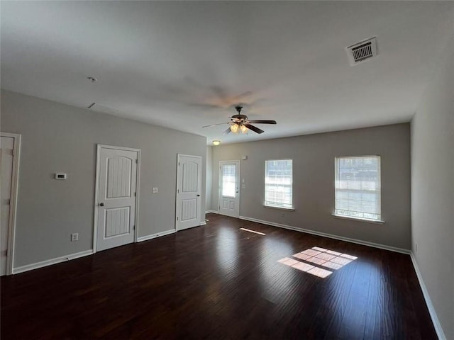 spare room with a ceiling fan, visible vents, baseboards, and wood finished floors