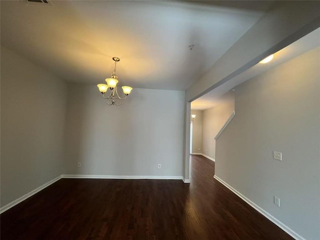 empty room with dark wood-style floors, a chandelier, and baseboards