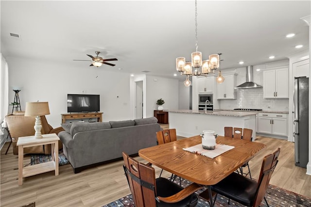 dining room featuring light wood finished floors, a chandelier, a ceiling fan, and recessed lighting