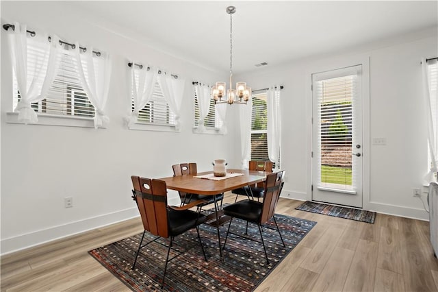 dining room with a chandelier, light wood finished floors, and baseboards