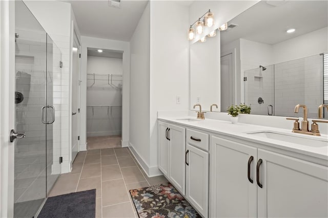 full bathroom with a stall shower, tile patterned flooring, double vanity, a spacious closet, and baseboards