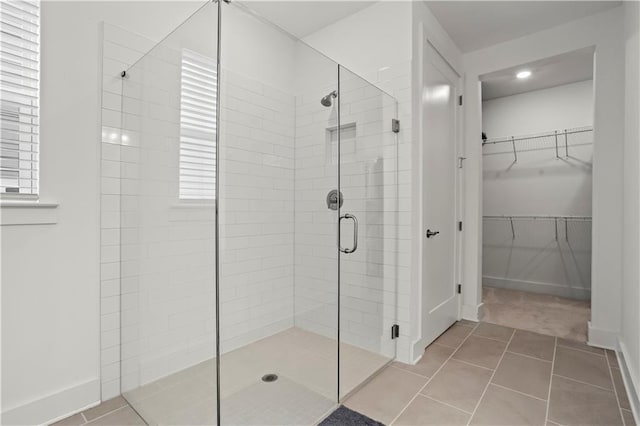 bathroom featuring a shower stall, a walk in closet, tile patterned flooring, recessed lighting, and baseboards
