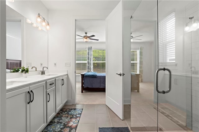 ensuite bathroom with a ceiling fan, double vanity, a shower with door, and tile patterned flooring