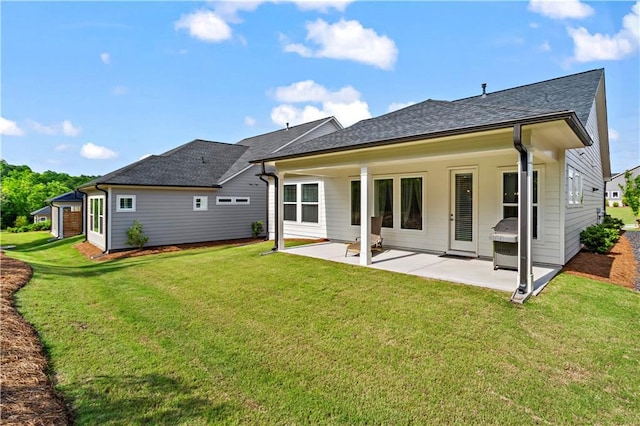 back of property with a patio area, a yard, and a shingled roof