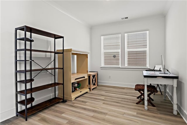 office area with light wood-style floors, baseboards, and crown molding