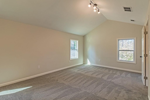 carpeted empty room with lofted ceiling and rail lighting