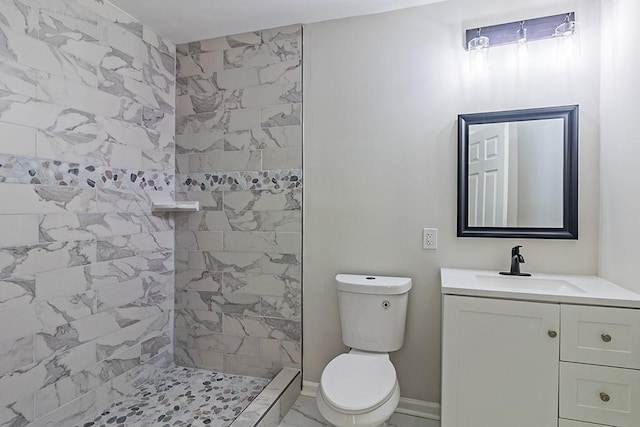 bathroom featuring toilet, tiled shower, and vanity