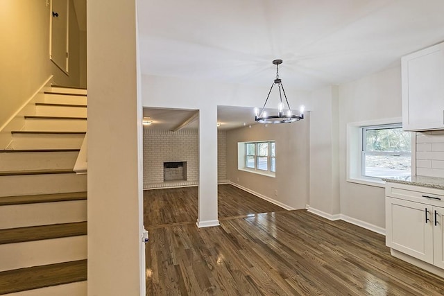 interior space with dark wood-type flooring, a fireplace, and an inviting chandelier