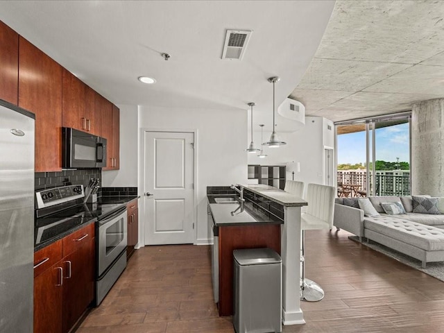 kitchen featuring a sink, visible vents, open floor plan, dark countertops, and appliances with stainless steel finishes