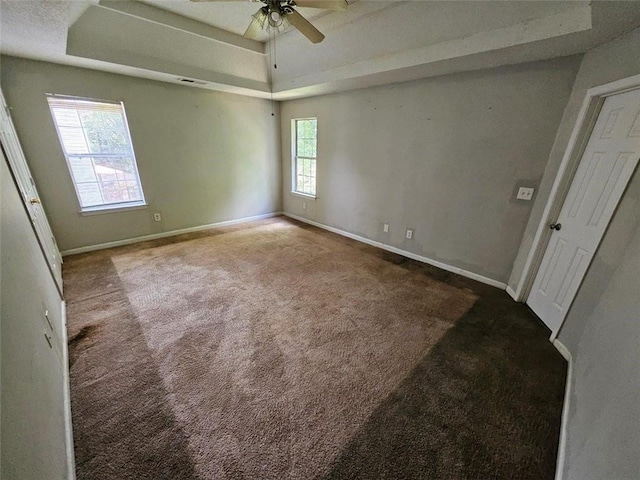 carpeted spare room featuring a tray ceiling and ceiling fan