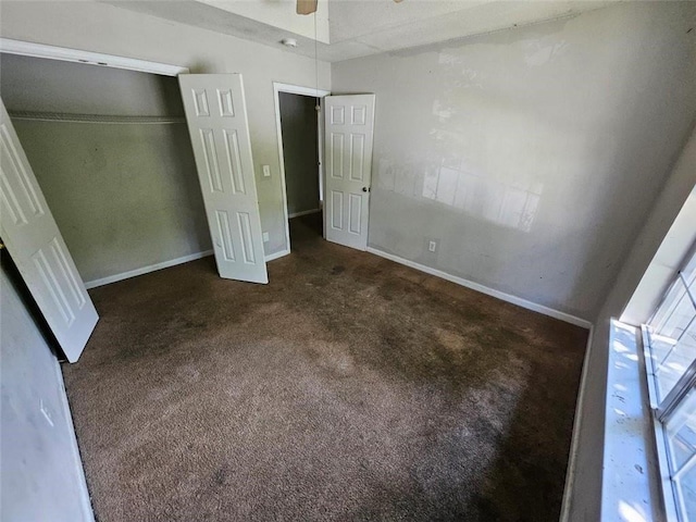 unfurnished bedroom with a closet, ceiling fan, and dark colored carpet