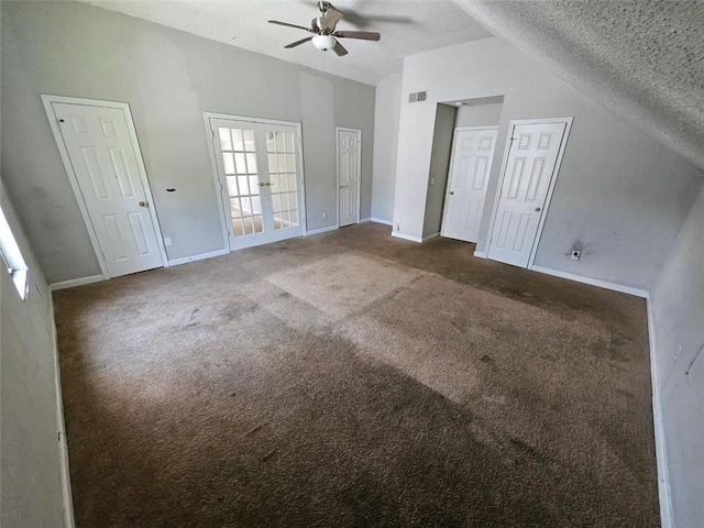 interior space with french doors, dark carpet, vaulted ceiling, a textured ceiling, and ceiling fan