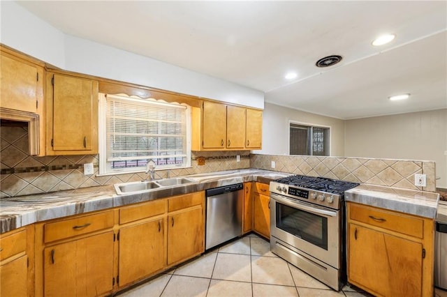 kitchen with light tile patterned flooring, sink, appliances with stainless steel finishes, tile counters, and backsplash